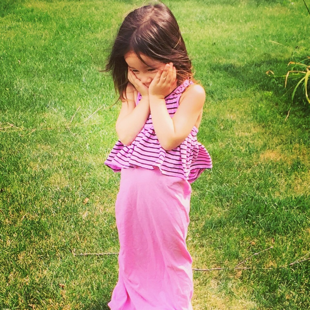 child wearing pink clothes and touching her face