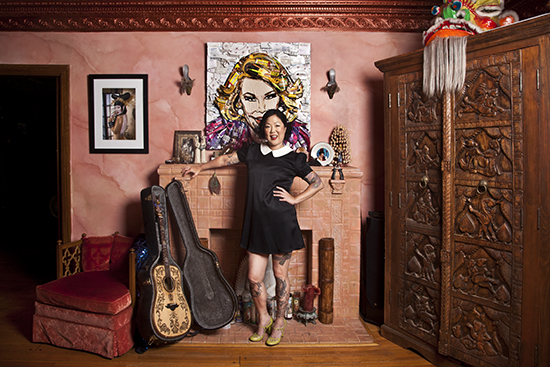 MARGARET CHO wearing a black dress and leaning on a wall