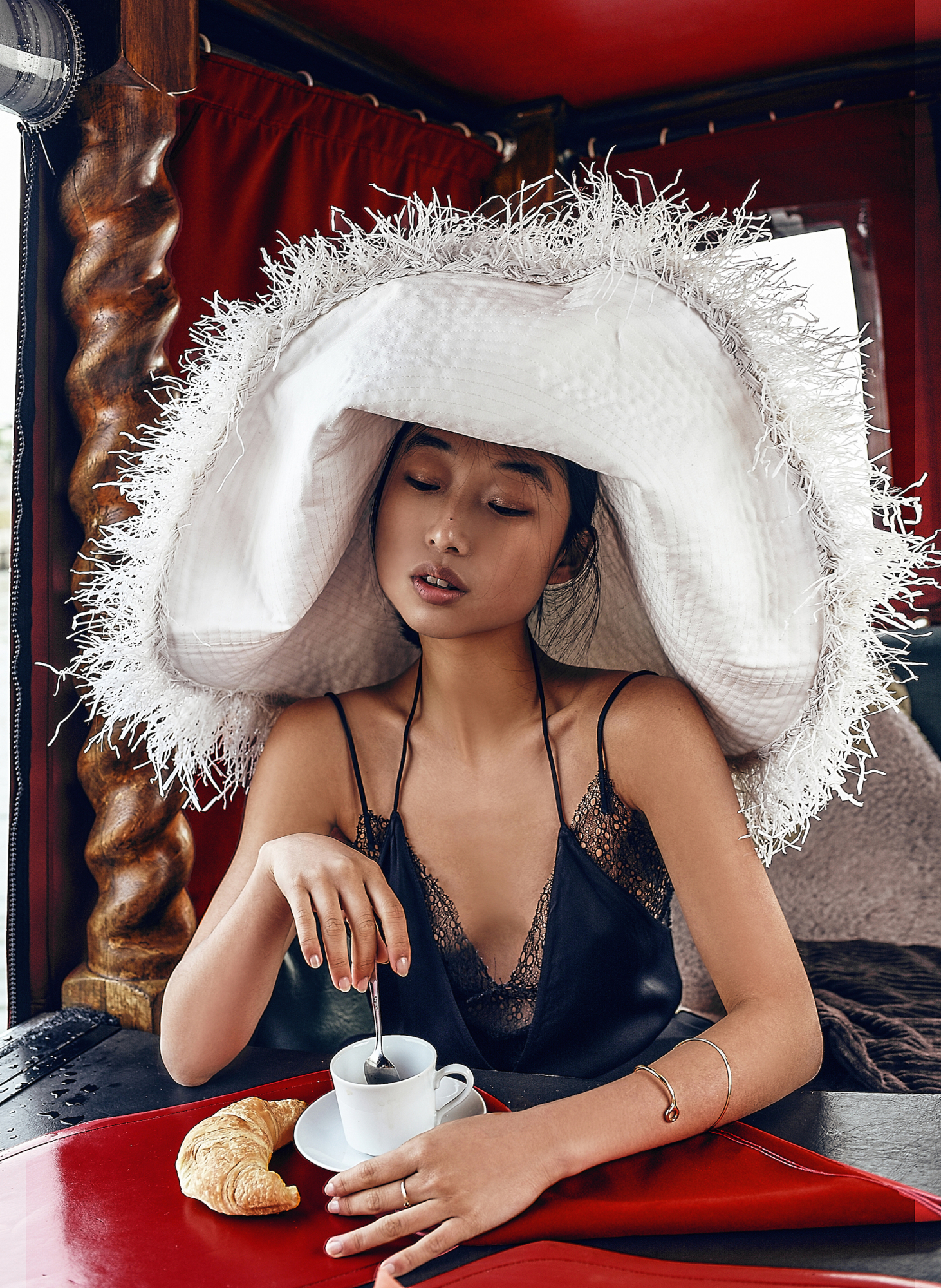 woman wearing cape and eating croissant and drinking tea