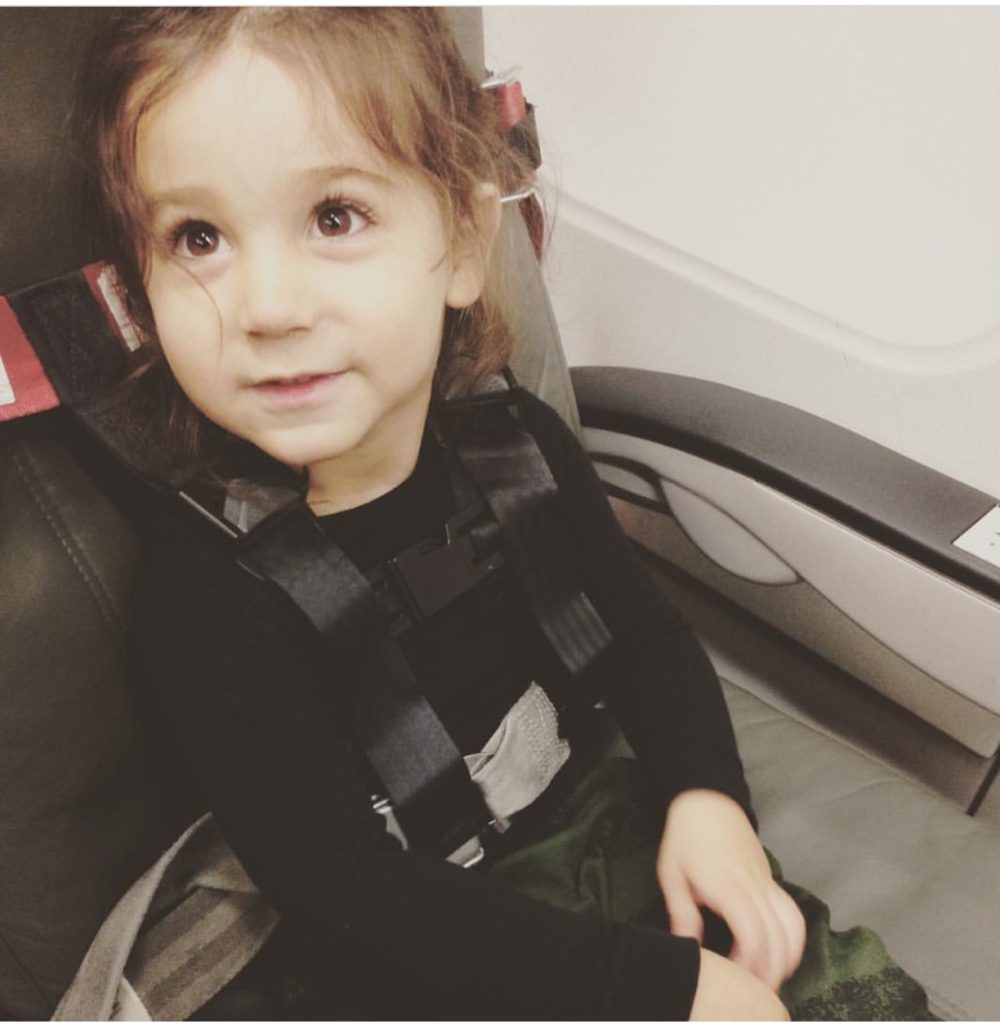 kid sitting in an airplane with mom sharing TRAVELING WITH A TODDLER