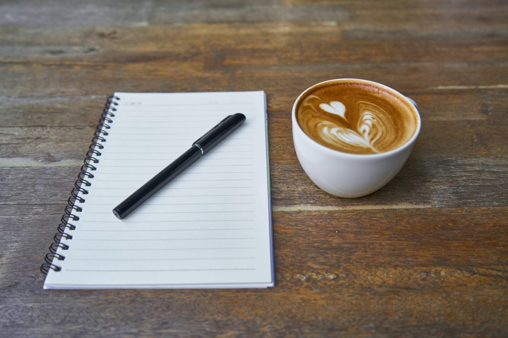 notebook, pen, and coffee for OUR NEXT 100 DAYS