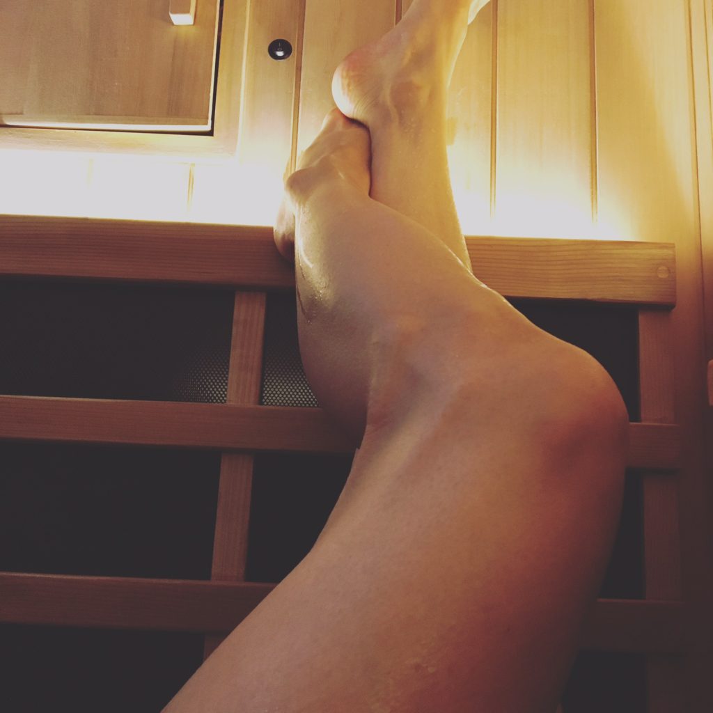 woman hanging her legs while doing infrared sauna