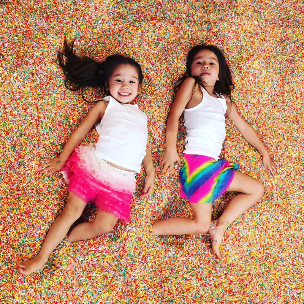 two kids laying down in colorful sand