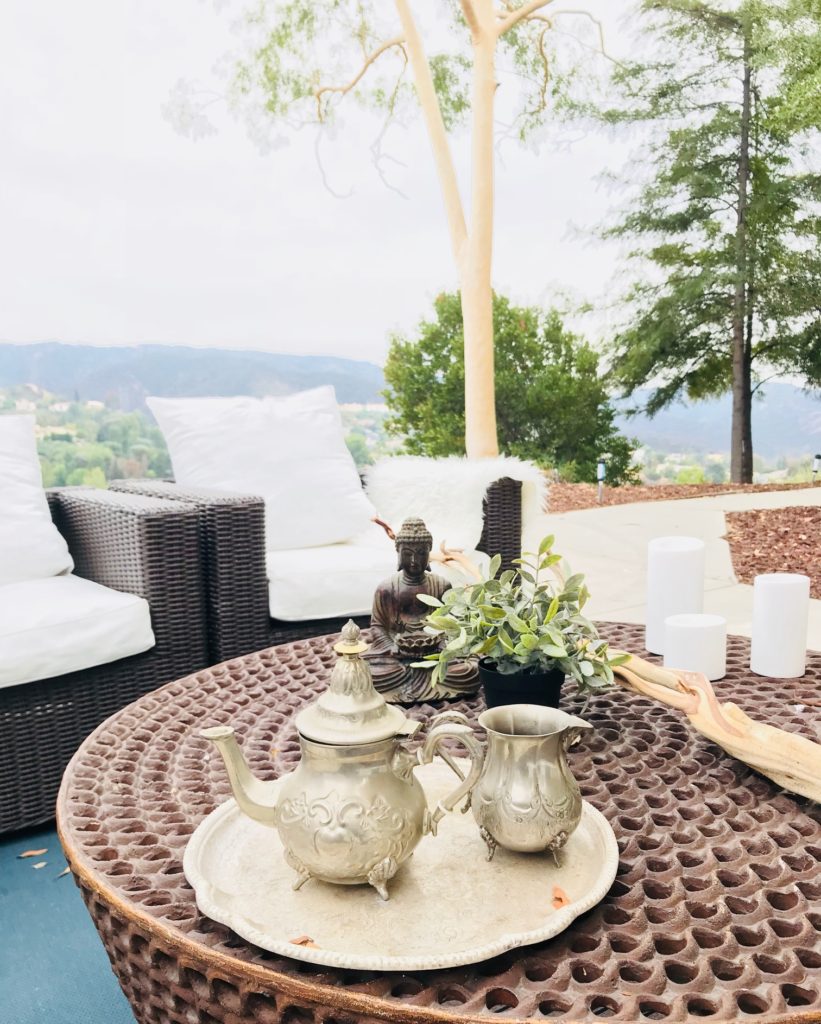 round table with tea cup and candles and two chairs with white cushions and pillows